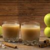 green apples, cinnamon sticks, and two glasses of applesauce on a table