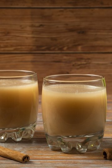green apples, cinnamon sticks, and two glasses of applesauce on a table
