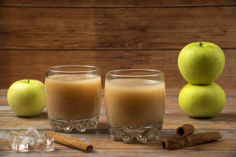 green apples, cinnamon sticks, and two glasses of applesauce on a table
