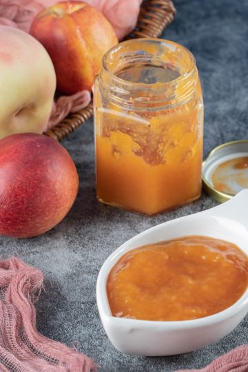apples in a wooden basket and applesauce in a confiture and a sauce cup